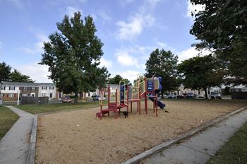 A playground with a red swing set and a blue slide.
